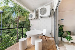 Relax on the breezy balcony, where a curved stone table and tropical greenery create the perfect setting for morning coffee or evening drinks.