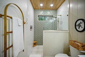 Step into spa-like serenity - a stunning sage green herringbone tile shower with cozy plaid tile floors and timeless charm.
