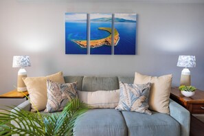 This plush seafoam couch with beach-themed pillows and a striking Molokini wall canvas offers the perfect island-inspired setting for unwinding with family.
