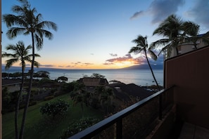 Evening ambiance meets luxury in this coastal-chic living room with full ocean views and tropical island decor.