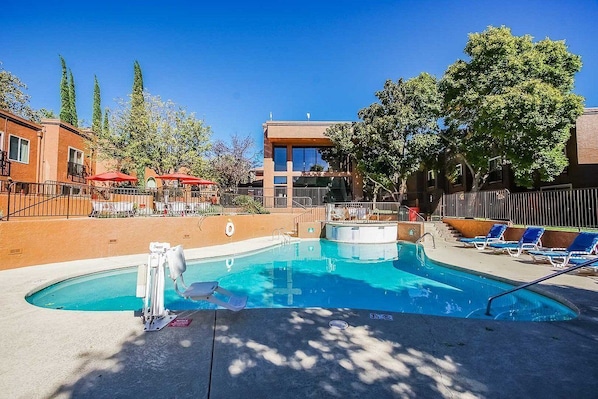 Enjoy the sunny outdoor pool area complete with a hot tub and inviting lounge chairs, perfect for soaking up the sun.