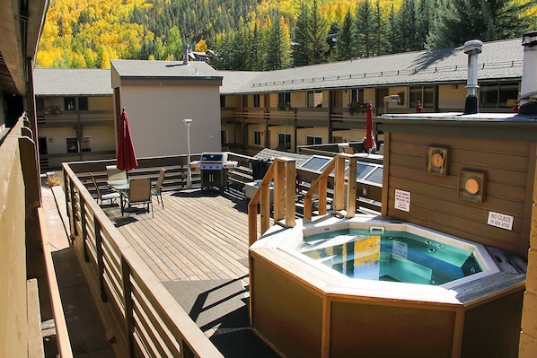 Enjoy a relaxing retreat at this mountain resort featuring a shared BBQ space, shared hot tubs, and a cozy outdoor deck with picturesque views surrounded by vibrant autumn foliage.