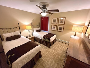 A warm and cozy twin bedroom equipped with two cozy beds and charming decor, ideal for kids or guests staying in the condo.