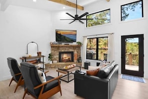 Relax in a cozy living room w/ stone fireplace, smart TV, sofa & forest views.