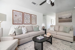 The living room boasts neutral colors and comfortable seating, creating a warm and inviting space to unwind.
