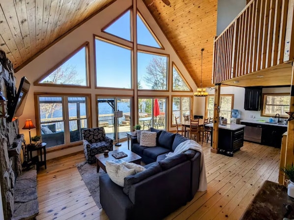 Open concept living, dining and kitchen with fireplace and doors to large deck