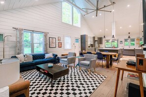 Open-concept layout with soaring ceilings and natural light flowing through the living room, dining area, and kitchen.