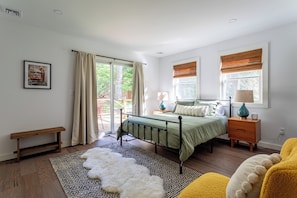 Spacious first-floor bedroom with a queen bed, large windows, and abundant natural light.