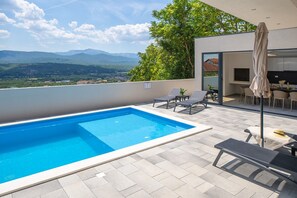 Überdachter Essbereich im Freien mit einem traditionellen Holz-/Holzkohlegrill