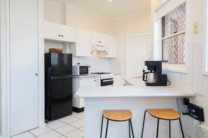 The compact kitchen makes mealtime easy, featuring a gas stove, oven, coffee machine, and microwave, along with a breakfast bar and stools for relaxed, casual dining.