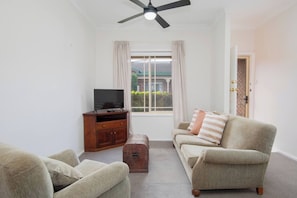 Step into the classic living area where a TV and plush seating create a homely atmosphere.