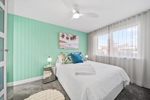 Bright bedroom with a seaside-inspired accent wall and plenty of natural light—perfect for relaxing