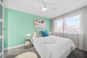 Bright bedroom with a seaside-inspired accent wall and plenty of natural light—perfect for relaxing