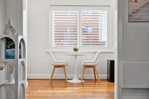 Dining area with a small table, two chairs, and a large window that fills the space with natural light