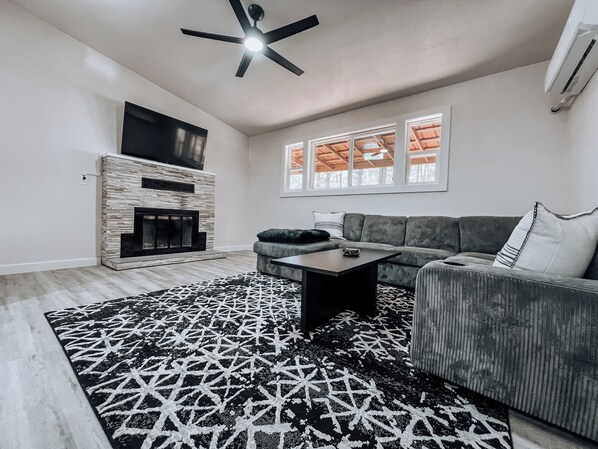 Modern, cozy living space with a wood burning fireplace and a large smart TV.
