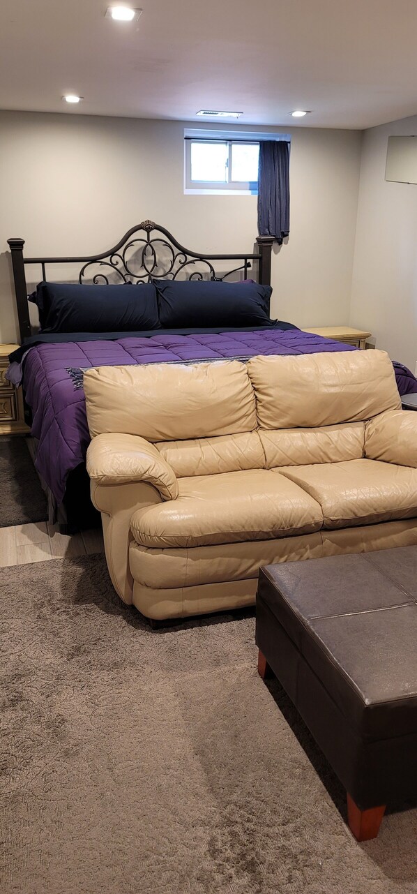 King sized bed with soft sofa and ottoman.