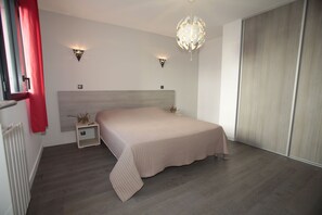 Bright and serene bedroom with plush bedding and direct access to natural light through large windows.