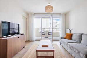 Spacious living area with TV and access to a private balcony for fresh air and relaxation (please note: some units may not include a balcony).