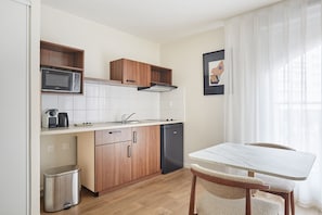 Fully equipped kitchenette with induction hob, microwave, fridge, kettle, and coffee maker for easy at-home meals.