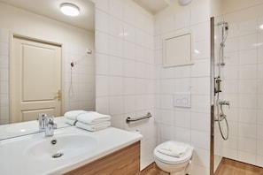 Modern, accessible bathroom with walk-in shower, support bars, and sleek white tiling for a seamless experience.
