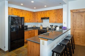 The fully equipped kitchen features a breakfast bar with barstool seating | Main Level