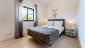 Charming double bedroom featuring minimalist decor, natural daylight, and elegant sheer curtains to create a calm, airy space.