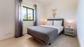 Charming double bedroom featuring minimalist decor, natural daylight, and elegant sheer curtains to create a calm, airy space.