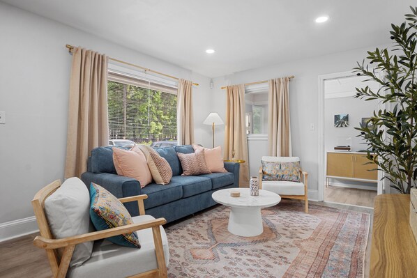 Living room with plush couch, wing chairs. and pastel hues