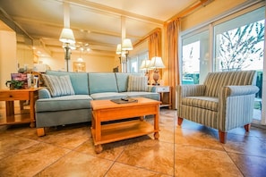 Unwind in the cozy living area featuring a queen sleeper sofa, ideal for accommodating extra guests while enjoying the bright natural light.
