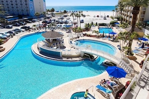 Discover the inviting pool area complete with a waterfall and a connecting bridge while enjoying direct beach access, perfect for family fun and relaxation.
