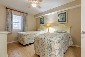 The serene guest room offers two twin beds, ideal for kids, surrounded by beach-inspired decor for a calming retreat.