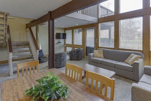 Embrace cozy mountain living in this spacious common area, complete with a fireplace and surrounded by large windows offering serene creekside views.