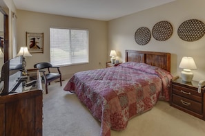 Retreat to the inviting bedroom, featuring a plush bed, smart TV, and large windows for natural light, while having easy access to in-suite washer/dryer facilities.