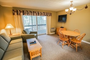 This inviting living area includes a comfortable sleeper sofa and dining space, leading out to a private deck for enjoying the serene surroundings.