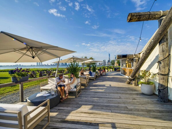 Deck seating with umbrellas and city skyline views