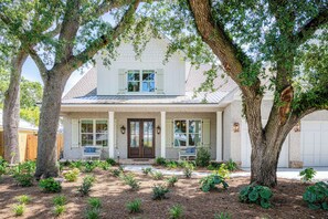 The front porch features benches on both sides of the entrance door to enjoy the beautiful curated landscaping