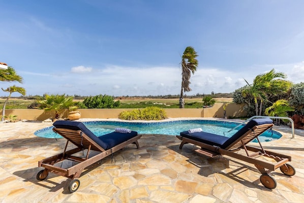 An elegant retreat with a private pool and stylish lounge chairs, offering serene views of lush greenery and the golf course. Perfect for unwinding in a peaceful, luxurious setting.