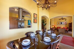 Inviting dining room with a wooden table for six, vibrant yellow walls, and charming lighting, offering a seamless connection to the kitchen and living room.