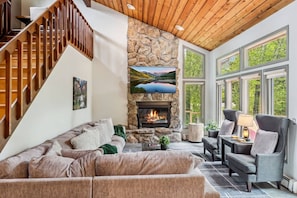 Spacious living room with fireplace, vaulted ceilings, smart TV and floor to ceiling windows