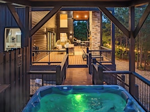Outdoor living space features private hot tub, spacious deck, and forest views.