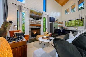 Open-concept living features vaulted ceilings, stone fireplace, and full kitchen.
