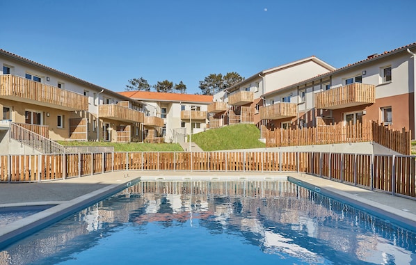 Dive into relaxation at the shared heated pool, nestled amid charming architecture and lush greenery, inviting you to unwind after a day at the beach.