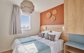 Relax in the inviting bedroom adorned with stylish decor and natural light, providing a serene retreat after a day of enjoying the beach and community amenities, including a fitness room.