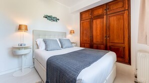 Comfortable master bedroom featuring a queen bed, warm lighting, and ample storage with wooden wardrobes. A serene retreat for restful nights. #BedroomComfort #CozyNights #HomeAwayFromHome #StylishStay