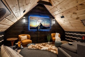 Enjoy movie nights in this impressive home theater, complete with a large illuminated screen, ambient lighting, and plush seating arranged within a stylish space featuring rustic wooden walls and ceilings. It's the perfect spot for entertainment and relaxa