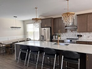 A chef’s dream kitchen featuring a massive island, high-end appliances, and elegant chandeliers.