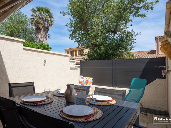 Shaded terrace with garden furniture, sun loungers, gas hob and awning