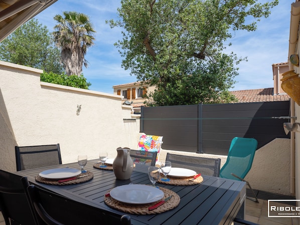 Shaded terrace with garden furniture, sun loungers, gas hob and awning