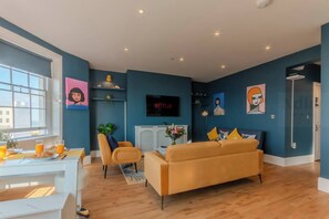 🛋 Living Area with Sea Views & Bold Style
Sink into plush seating in this vibrant, art-filled lounge featuring rich navy tones, striking portrait art, and a Smart TV with Netflix—perfect for cosy evenings after a day at the beach.
