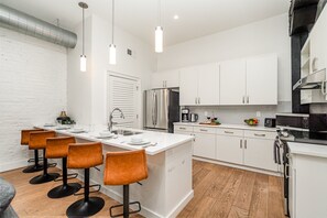 Fully equipped kitchen featuring stainless steel appliances, open counter space, and bar seating for 5 guests.